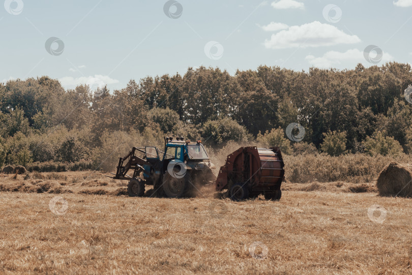 Скачать трактор в поле выбрасывает рулон сена фотосток Ozero