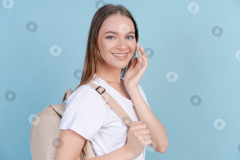 Скачать Счастливая молодая женщина в легкой одежде с рюкзаком за спиной позирует в студии фотосток Ozero
