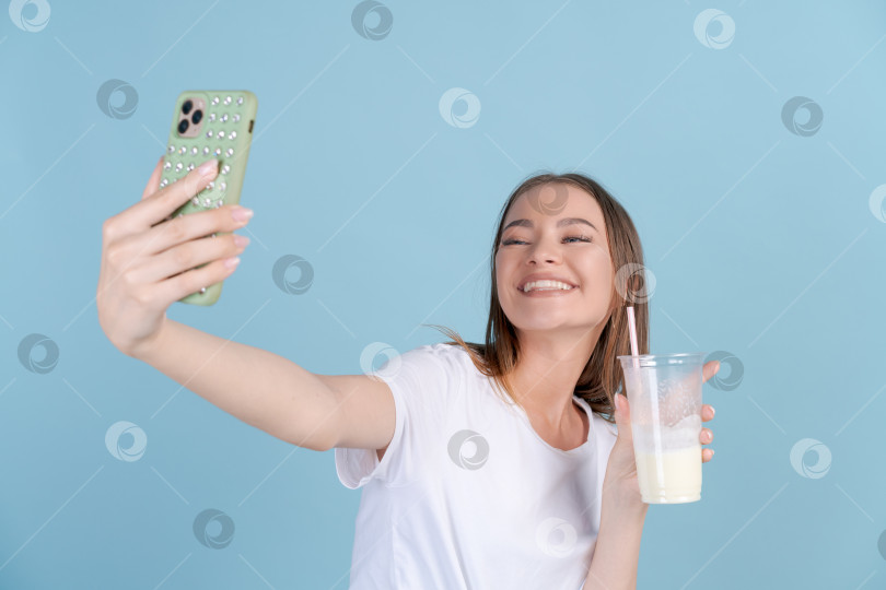 Скачать Счастливая красивая девушка фотографирует себя со свежим молочным коктейлем на мобильный телефон фотосток Ozero