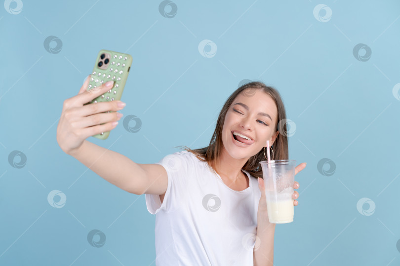 Скачать Счастливая красивая девушка фотографирует себя со свежим молочным коктейлем на мобильный телефон фотосток Ozero