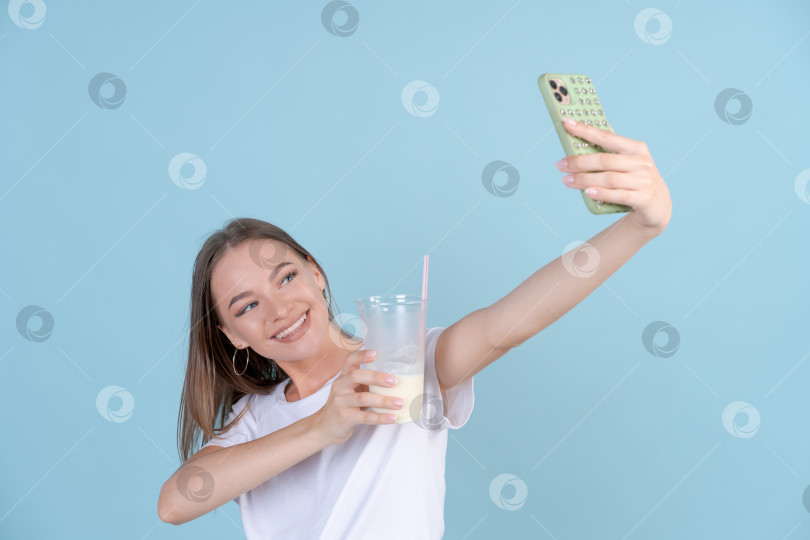 Скачать Счастливая красивая девушка фотографирует себя со свежим молочным коктейлем на мобильный телефон фотосток Ozero