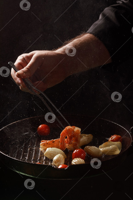 Скачать Шеф-повар готовит морепродукты, креветки на сковороде с овощами. фотосток Ozero