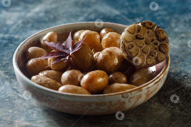 Скачать Отварной молодой картофель с маслом и обжаренным чесноком на деревянном блюде. фотосток Ozero