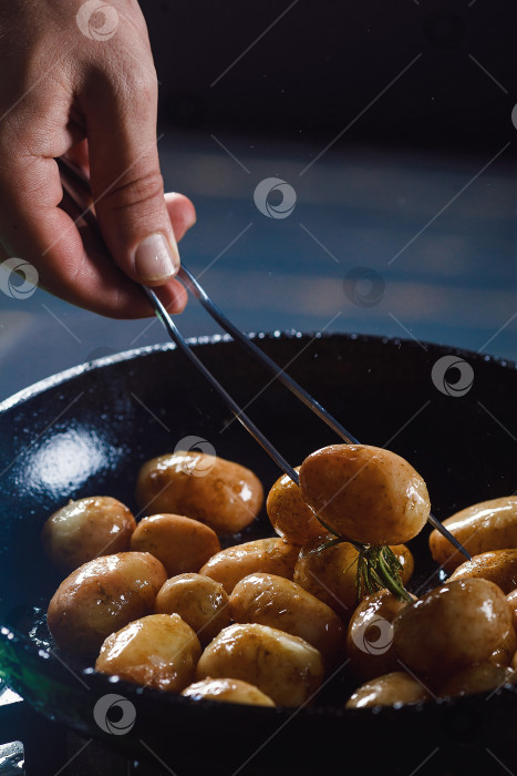 Скачать Отварной молодой картофель с маслом и обжаренным чесноком на деревянном блюде. фотосток Ozero