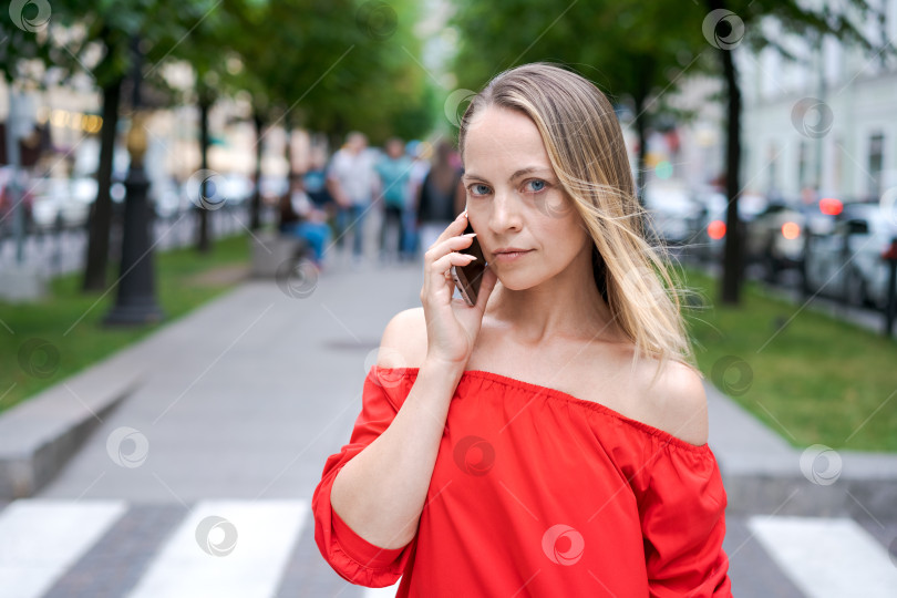 Скачать Белая женщина со смартфоном, стоящая на фоне размытой улицы фотосток Ozero