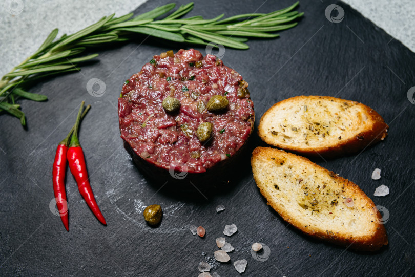 Скачать Тартар из говядины с каперсами и тостами на тарелке. фотосток Ozero