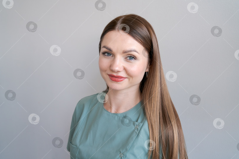 Скачать Портрет молодой красивой девушки-врача-косметолога в зеленой униформе в ярких фотосток Ozero