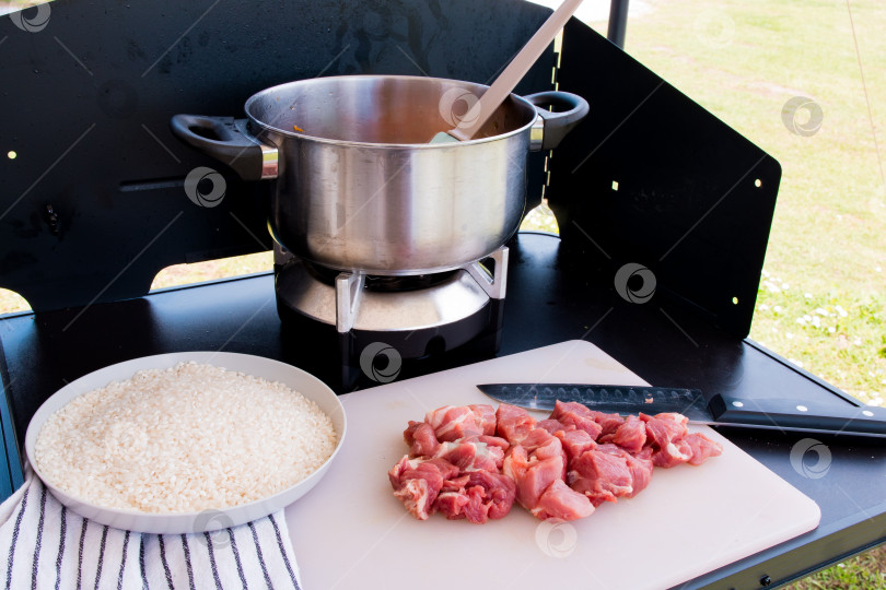 Скачать Приготовление на открытом воздухе. Тушеное мясо в горшочках с нарезанным кубиками мясом и рисом на разделочной доске фотосток Ozero