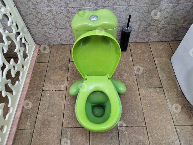 Скачать В ванной комнате стоит зеленый детский унитаз на фоне бежевой плитки фотосток Ozero