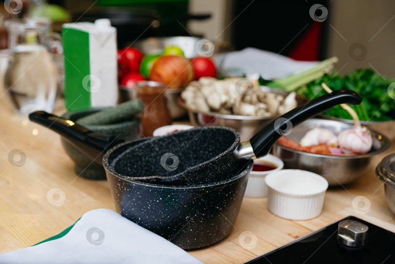 Скачать Стопка кастрюль с антипригарным покрытием на кухонном столе фотосток Ozero
