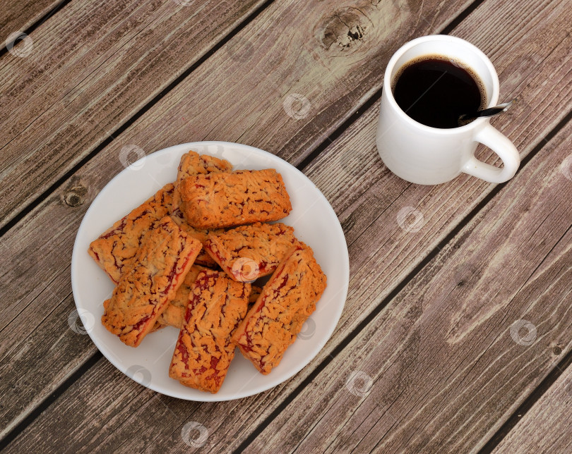 Скачать Песочное печенье с фруктовым джемом и чашка горячего черного кофе на деревянном столе. фотосток Ozero