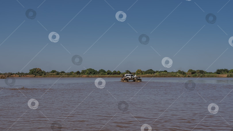 Скачать Паром с людьми и автомобилем пересекает африканскую реку. фотосток Ozero