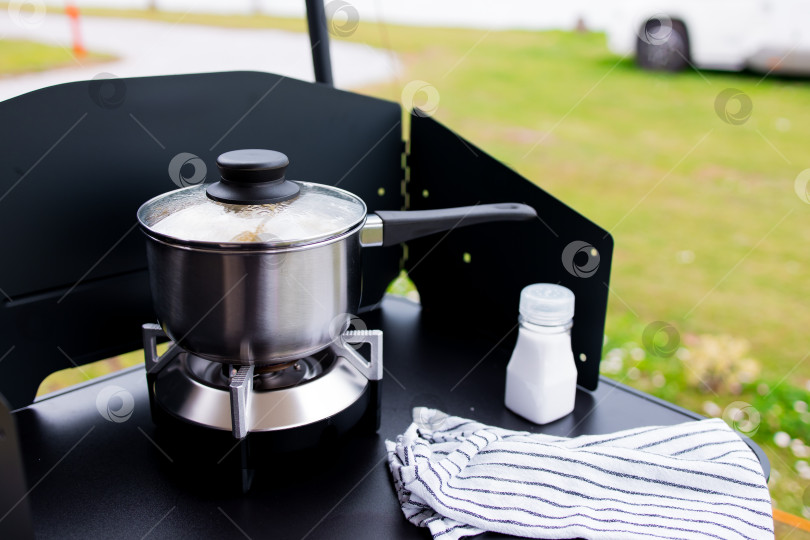 Скачать Сцена приготовления пищи на открытом воздухе с кастрюлей на переносной плите и солонкой на черной поверхности фотосток Ozero