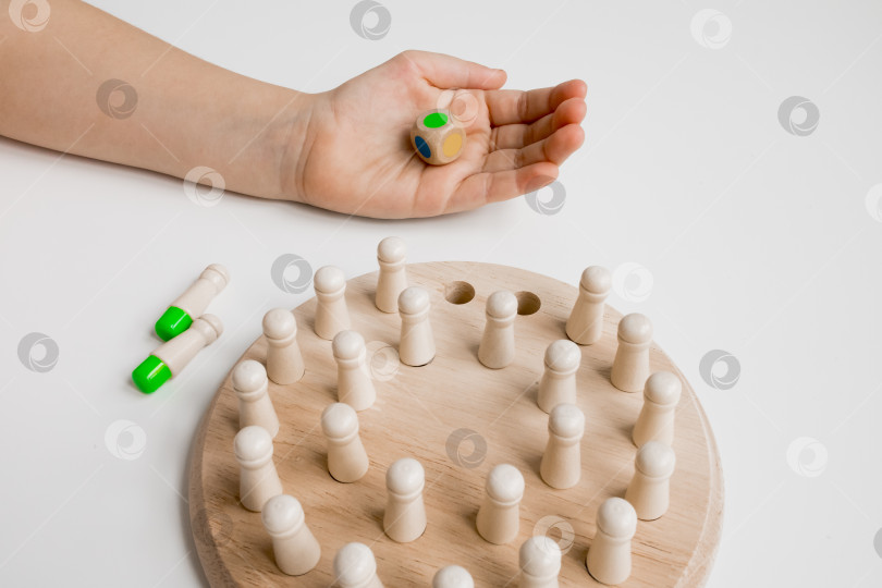 Скачать Детская рука с деревянными игровыми фигурками на круглой доске фотосток Ozero