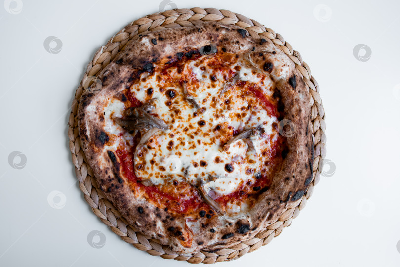 Скачать Вкуснейшая неаполитанская пицца с моцареллой и помидорами на плетеной салфетке фотосток Ozero