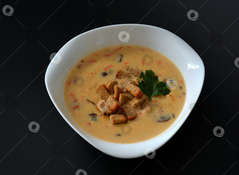 Скачать Сырный крем-суп с гренками и грибами в глубокой тарелке на черном фоне. фотосток Ozero