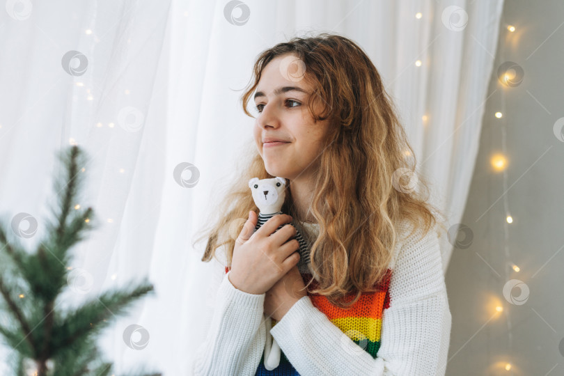 Скачать Красивая девочка-подросток с игрушечным медведем сидит на подоконнике в уютной детской комнате фотосток Ozero