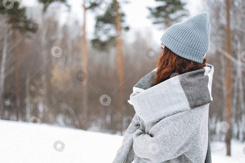Скачать Привлекательная молодая женщина в вязаной шапочке и уютном сером свитере в зимнем парке фотосток Ozero
