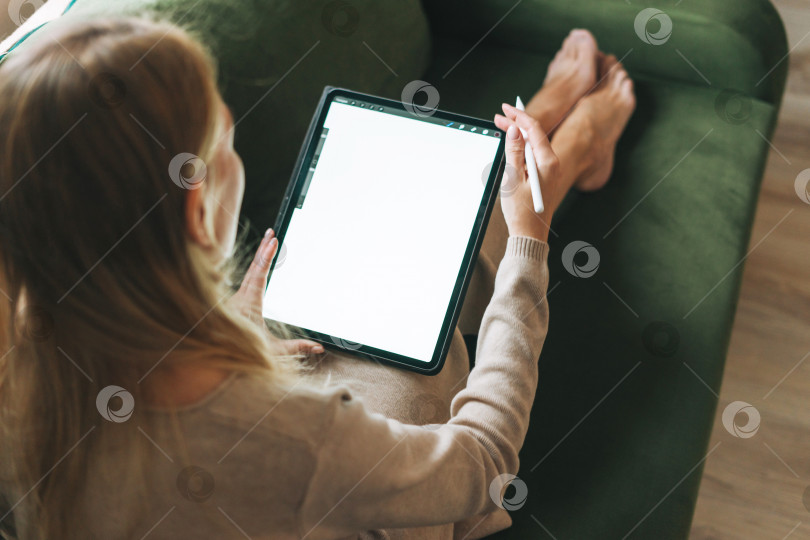 Скачать Красивая молодая блондинка художник-иллюстратор рисует на планшете с белым экраном в домашнем макете фотосток Ozero