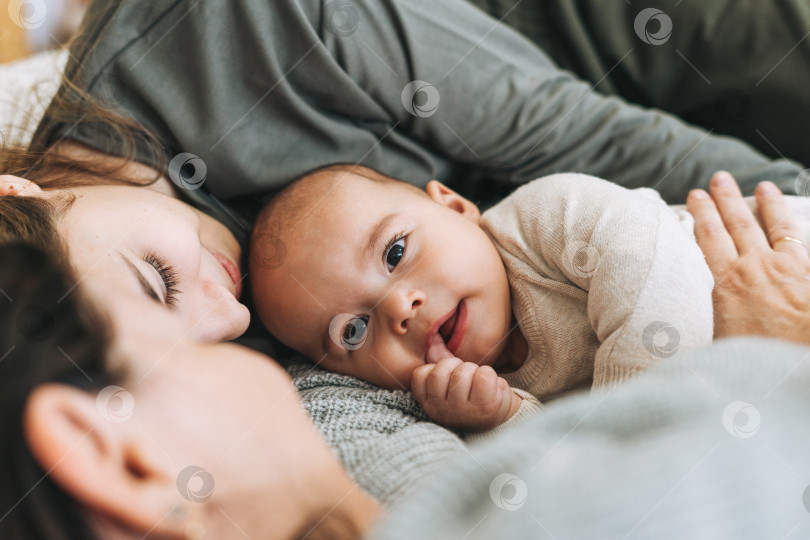 Скачать Настоящая семья из молодой мамы и двух детей разного возраста девочки-подростка и маленького мальчика развлекается на кровати фотосток Ozero