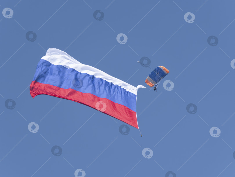 Скачать ЖУКОВСКИЙ, РОССИЯ - 01 сентября 2021 года: Парашютист с огромным российским флагом в небе фотосток Ozero