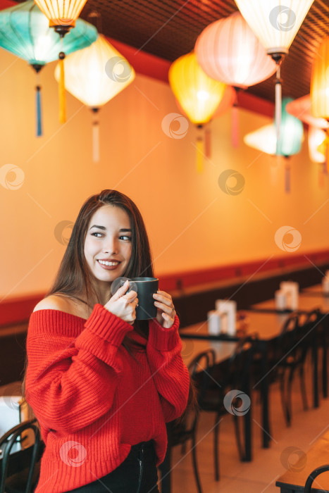 Скачать Красивая улыбающаяся молодая азиатка в красном с чашкой чая в китайском ресторане фотосток Ozero