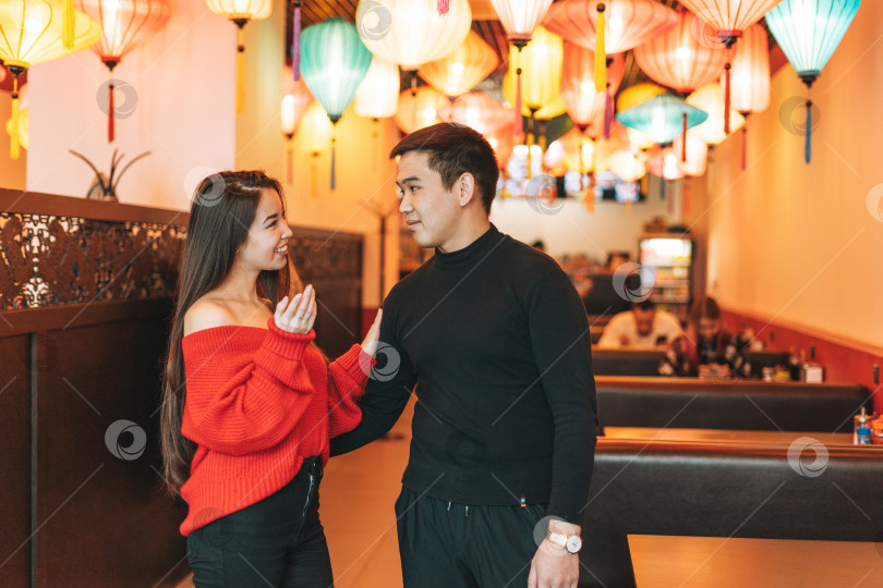 Скачать Красивая молодая азиатская пара в красной одежде дарит в праздничном китайско-вьетнамском ресторане красочные бумажные фонарики, празднуя китайский Новый год фотосток Ozero