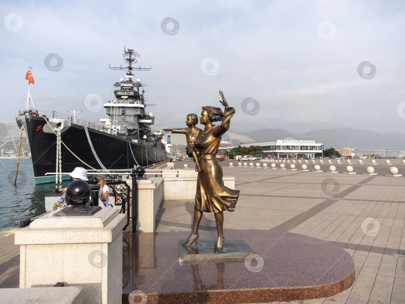 Скачать Новороссийск, Россия - 18 августа 2024 года: Вид на памятник жене моряка и крейсеру "Михаил Кутузов" на набережной фотосток Ozero
