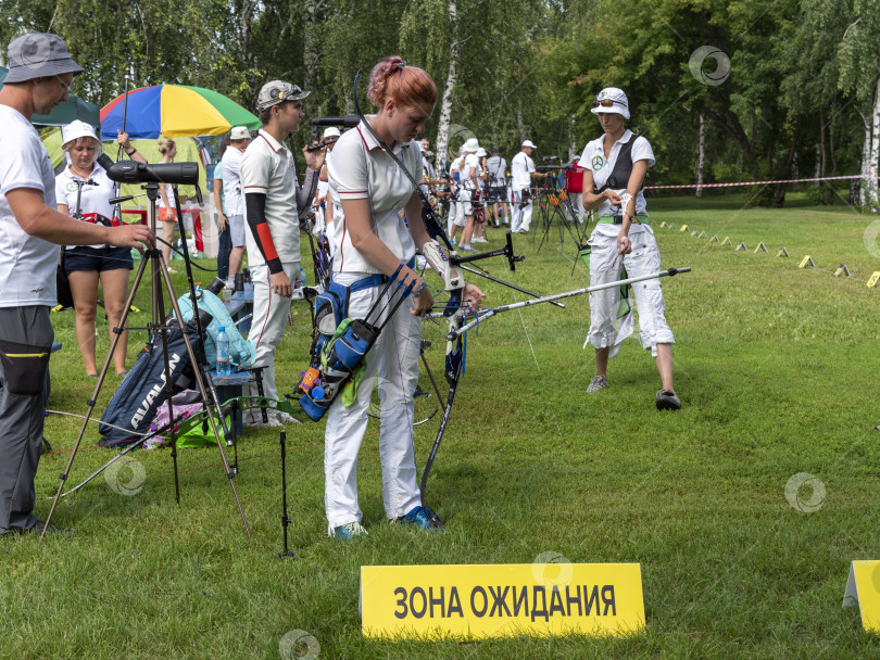 Скачать БАРНАУЛ - 6 августа: Привлекательный мужчина-лучник сгибает лук и целится в мишень 6 августа 2023 года в Барнауле, Россия. фотосток Ozero