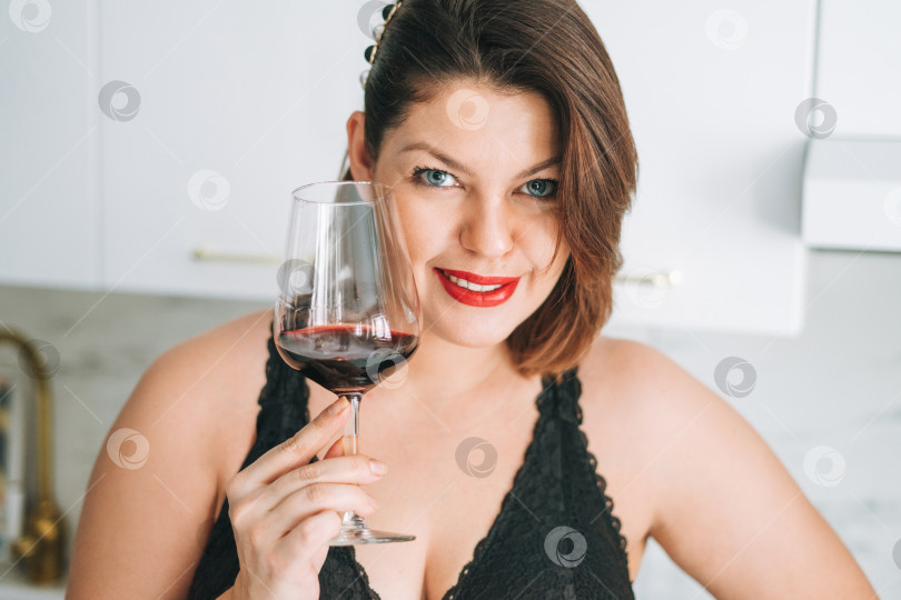Скачать Красивая счастливая чувственная молодая брюнетка с позитивным телосложением плюс размер с бокалом красного вина наслаждается своей жизнью дома фотосток Ozero