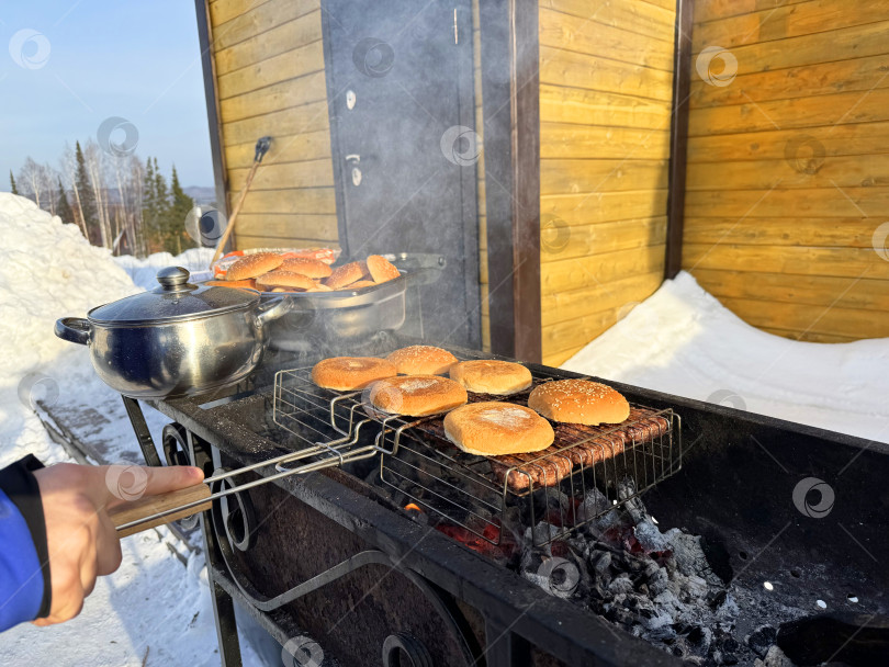 Скачать Зимнее барбекю со свежими булочками на гриле на открытом воздухе в заснеженной обстановке фотосток Ozero