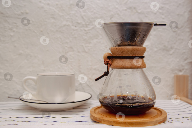 Скачать Стеклянная кофеварка chemex с вкусным капельным кофе в зернах на белом столе. Место для текста фотосток Ozero