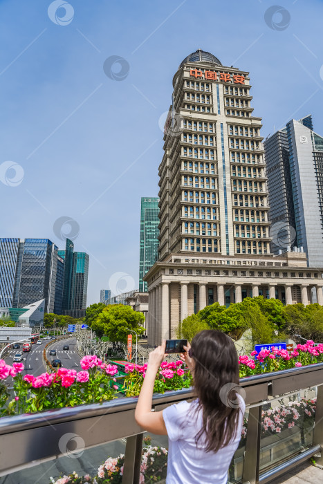 Скачать Шанхай, Китай - 1 апреля 2025 года: турист фотографирует здание Ping An Group с красной вывеской Ping An Insurance в Пудуне в солнечный день. фотосток Ozero