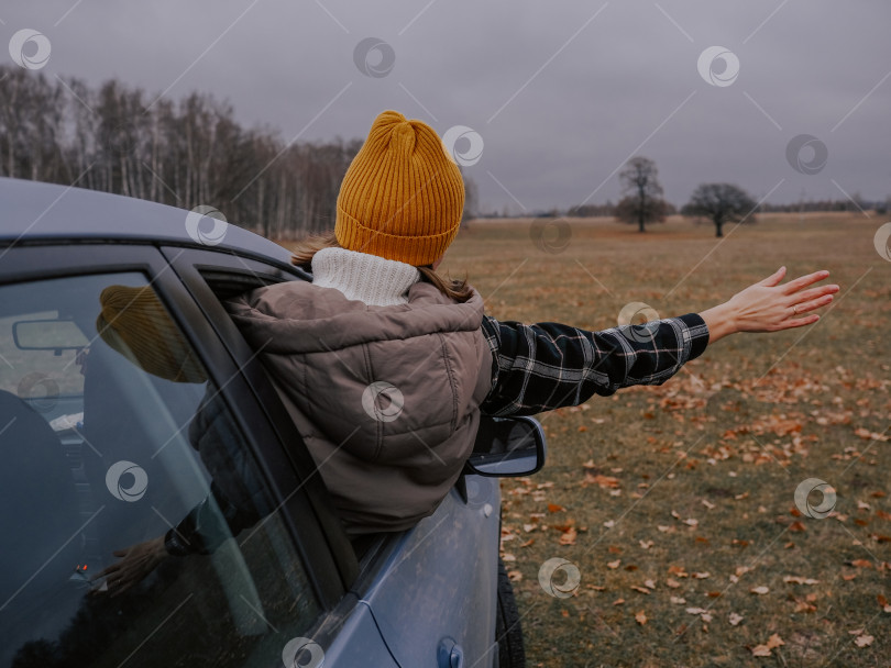 Скачать Девушка, путешествующая на машине осенью. Счастливая женщина, выглядывающая из окна автомобиля фотосток Ozero