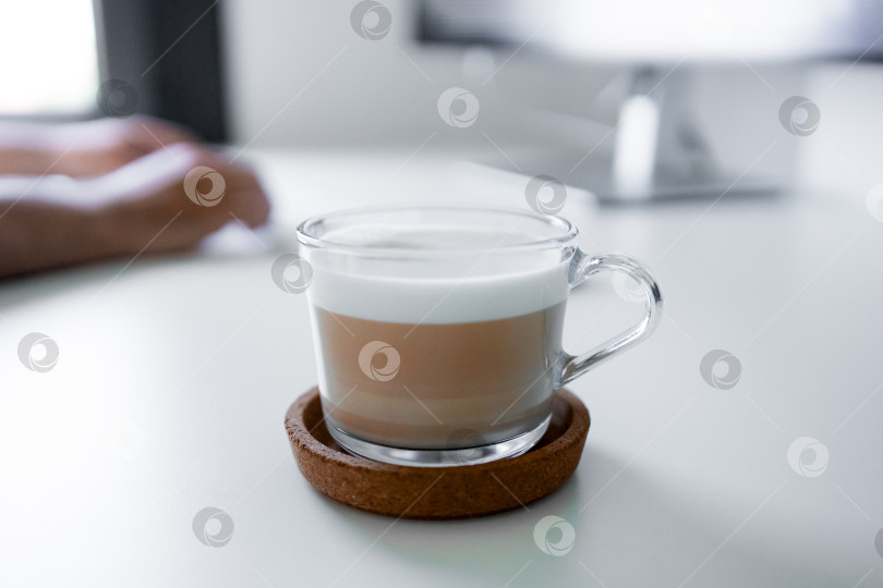 Скачать Капучино в прозрачной стеклянной чашке на столе руками человека фотосток Ozero