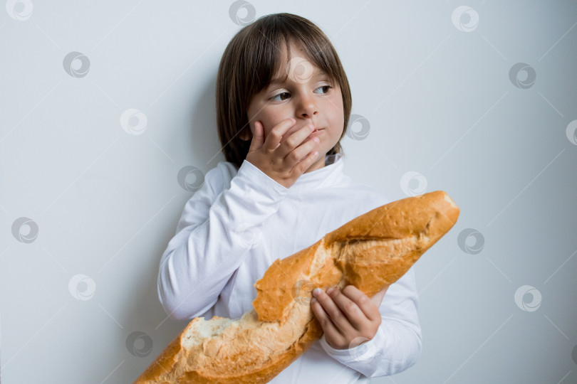 Скачать Маленький кавказский ребенок держит багет на белом фоне фотосток Ozero