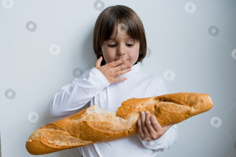 Скачать Молодой кавказец наслаждается багетом в повседневной белой рубашке фотосток Ozero