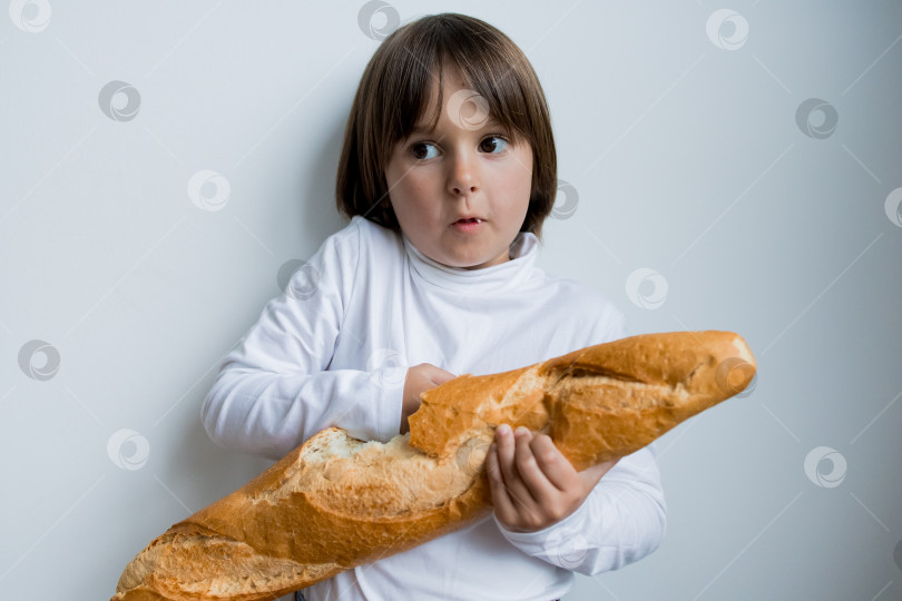 Скачать Кавказский ребенок держит багет на белом фоне фотосток Ozero