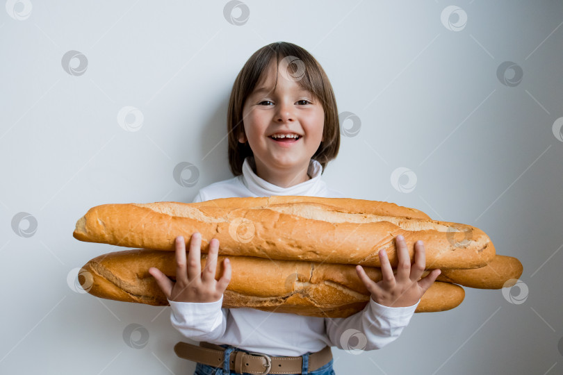 Скачать Счастливый кавказский ребенок держит багеты на белом фоне фотосток Ozero