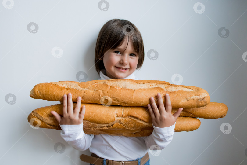 Скачать Белая девочка улыбается, держа в руках багеты на белом фоне фотосток Ozero