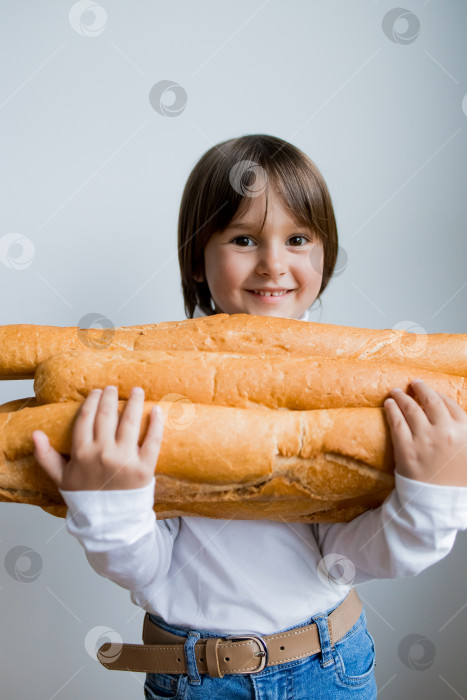 Скачать Молодая кавказская девушка улыбается, держа в руках большие багеты на белом фоне фотосток Ozero