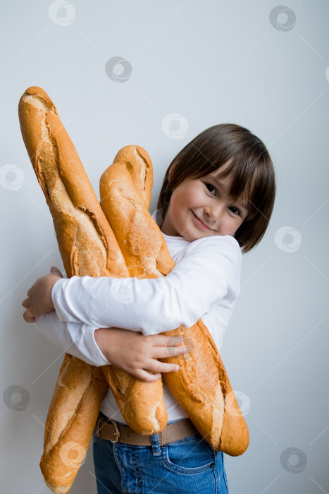 Скачать Счастливый кавказский ребенок держит в руках багеты и радостно улыбается фотосток Ozero