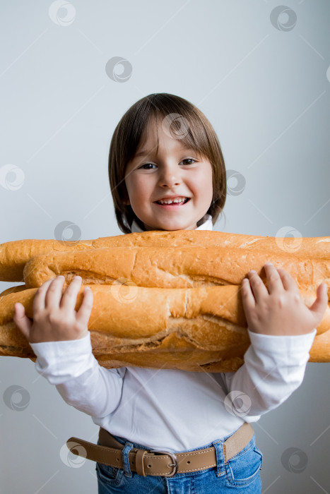 Скачать Улыбающийся кавказский ребенок держит в руках большие багеты на белом фоне фотосток Ozero