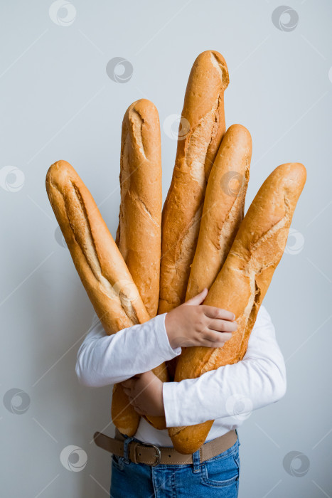 Скачать Человек, несущий несколько багетов, в белой рубашке и джинсах на белом фоне фотосток Ozero