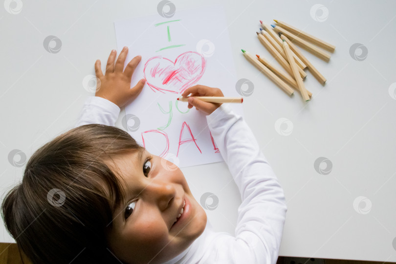 Скачать Испаноязычный ребенок рисует открытку на день отца с сердечком на белой бумаге фотосток Ozero