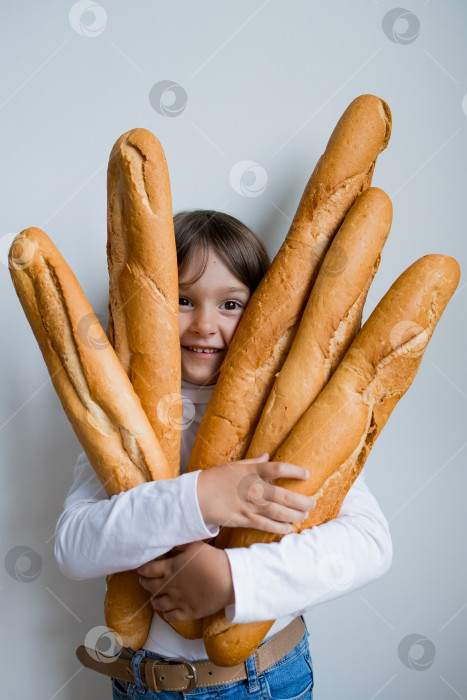 Скачать Счастливый кавказский ребенок держит в руках свежие багеты на белом фоне фотосток Ozero
