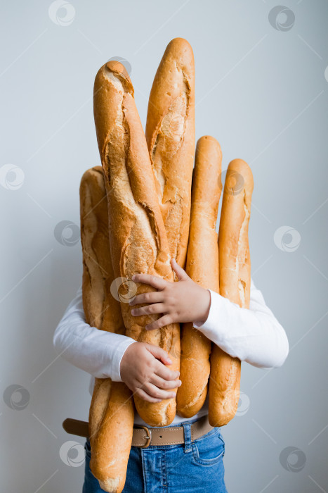 Скачать Ребенок держит в руках несколько багетов на белом фоне фотосток Ozero