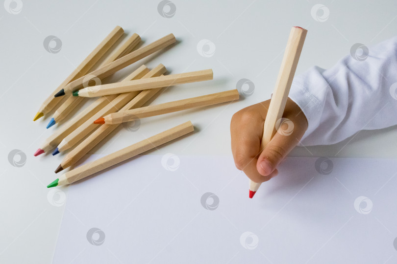 Скачать Ребенок рисует цветными карандашами на белой бумаге фотосток Ozero