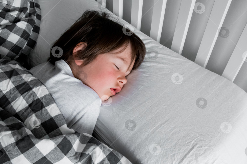 Скачать Спокойный сон. Маленький кавказский ребенок уютно спит в клетчатом одеяле фотосток Ozero