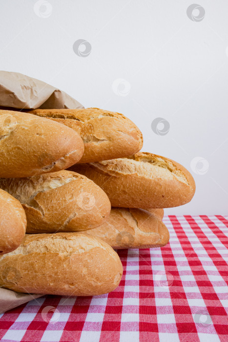 Скачать Свежие багеты на красной клетчатой скатерти в загородной обстановке кухни фотосток Ozero